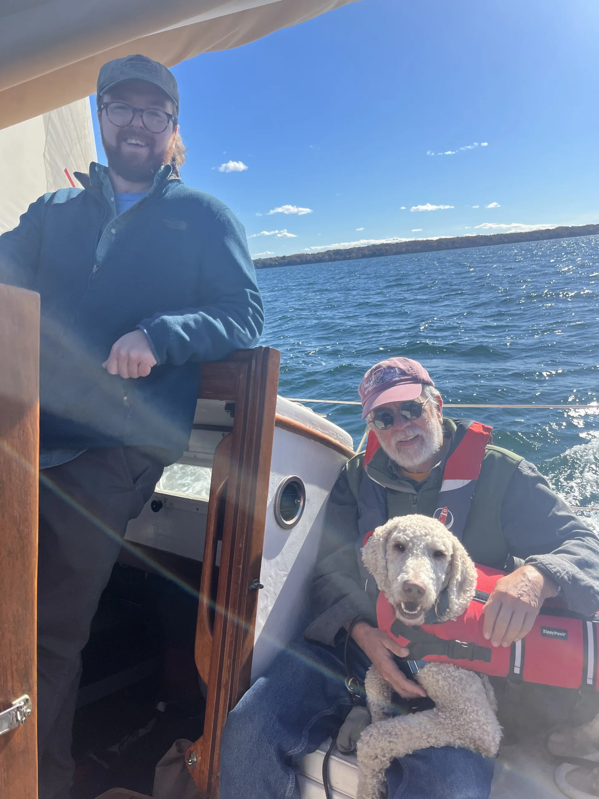 2 people and a dog smiling on a boat