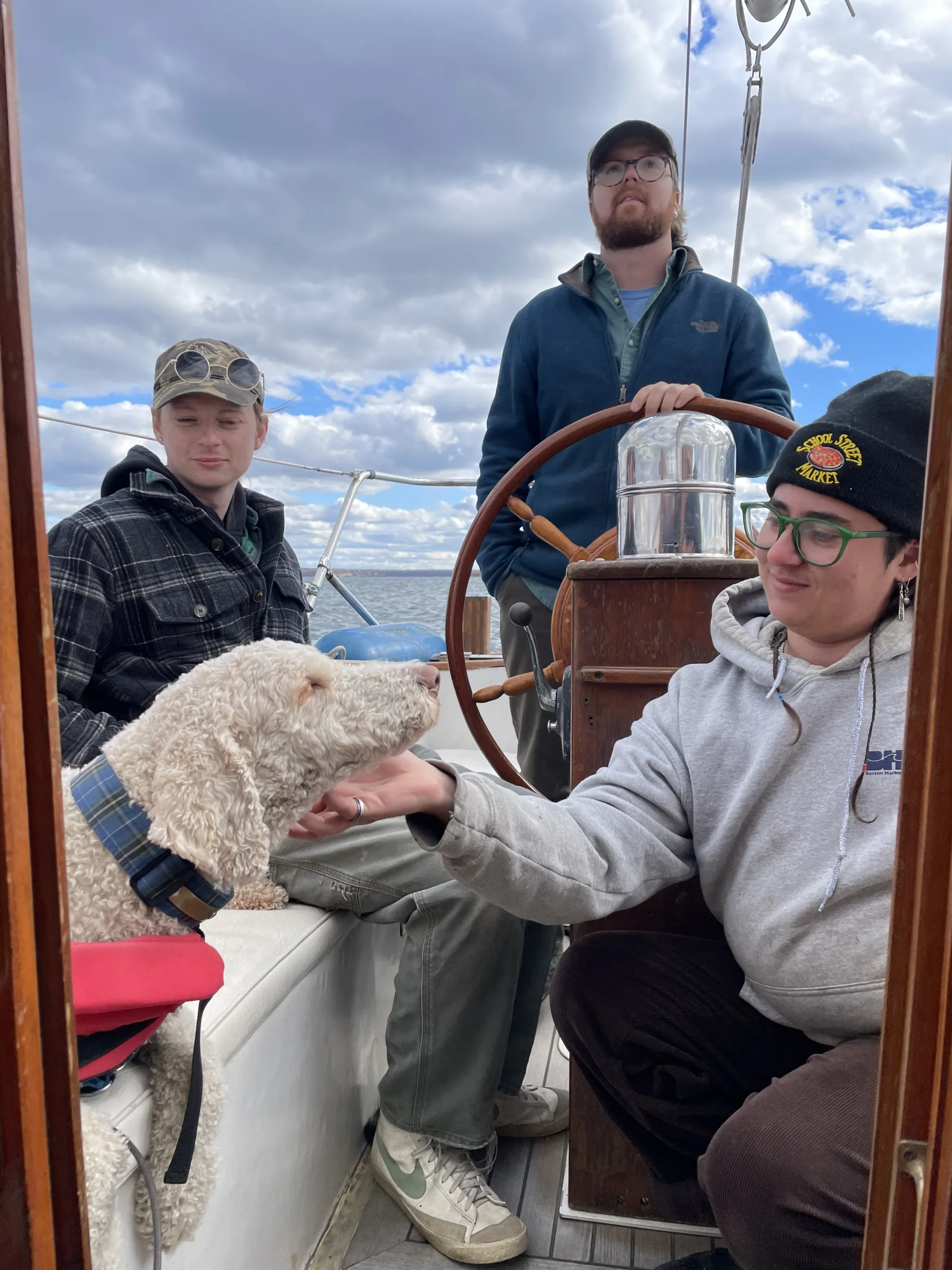 three people and a dog in a boat cockpit