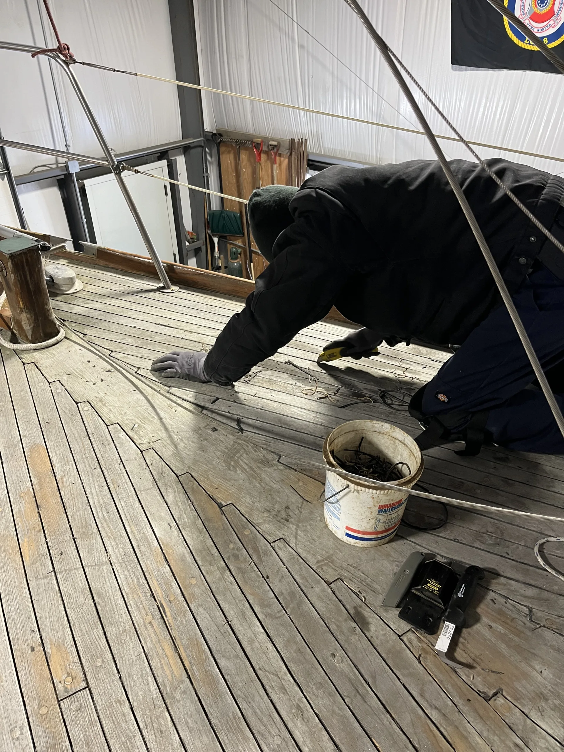 person cleaning caulk out of deck seams
