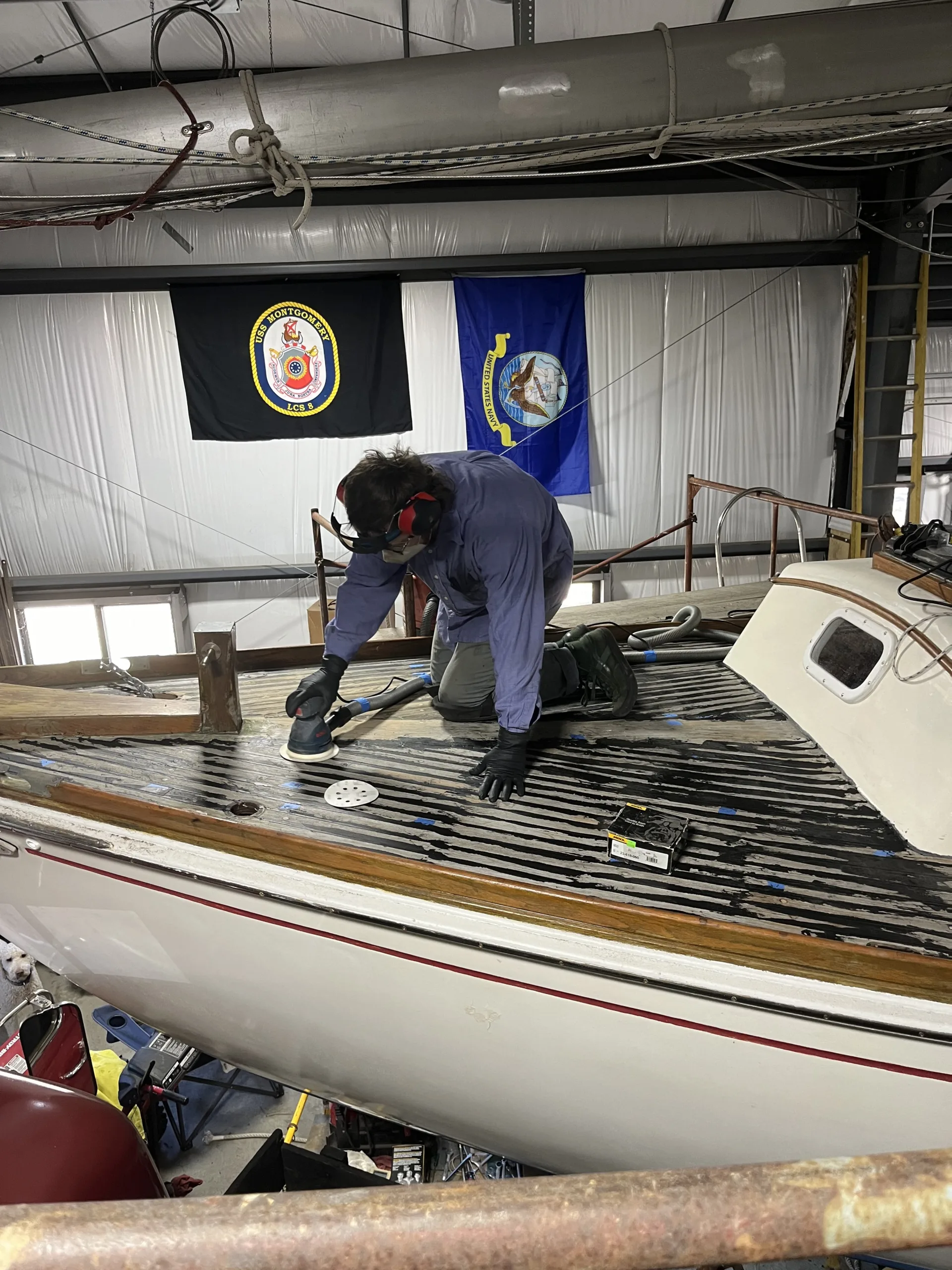 person sanding sailboat deck